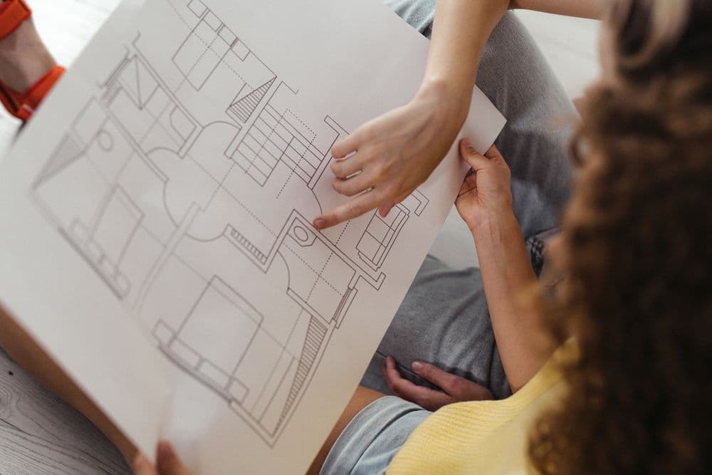 People reviewing a black-and-white architectural floor-plan print
