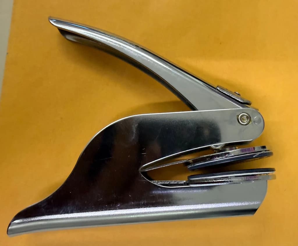 The shop’s chrome handheld embossing seal, with its circular insert fitted