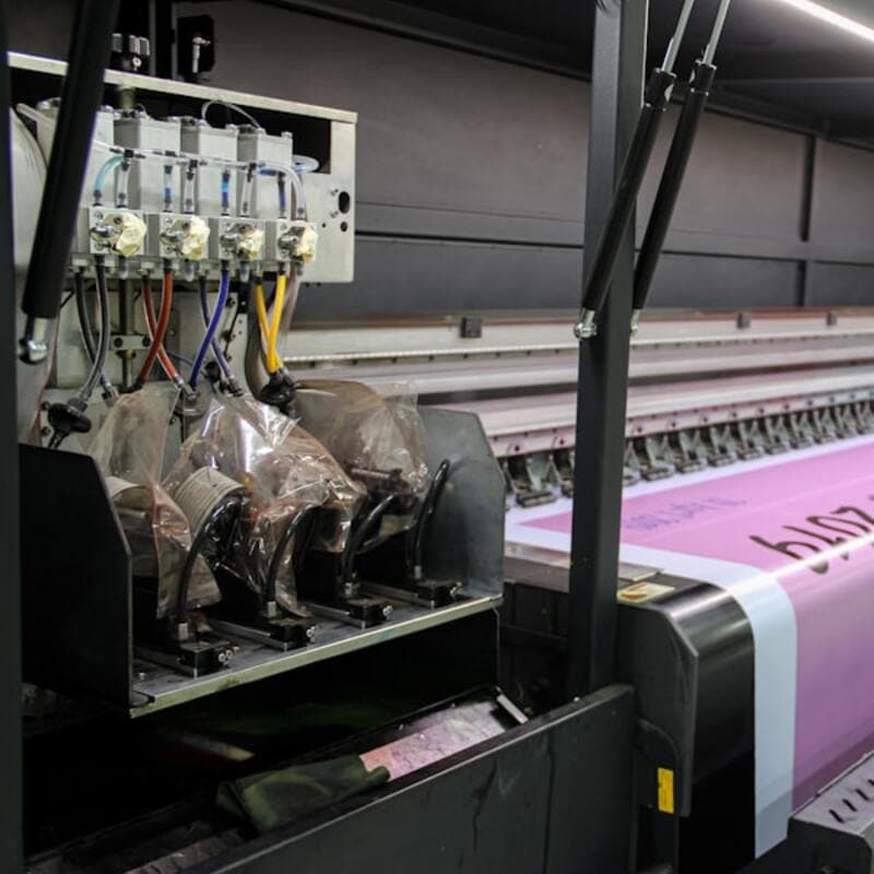 A wide-format printer running a roll of material through its print head